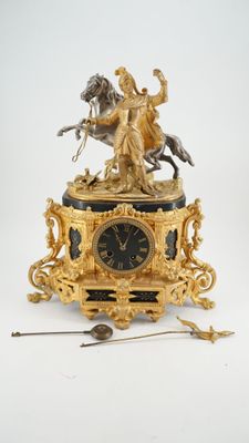 une horloge en or surmontée d'une statue représentant un homme à cheval