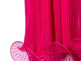 pink pleated dress hanging on a hanger against a white background