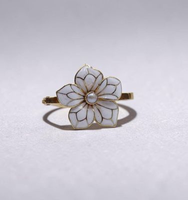 une bague en or surmontée d'une fleur blanche