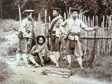 a group of men posing for a picture in front of a fence