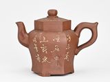 brown ceramic teapot with chinese writing on it on a white surface