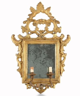 a gold framed mirror with a candle holder on it