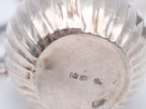 a silver cup sitting on a table with a spoon next to it
