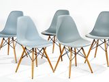 Quatre chaises bleues aux pieds en bois sont alignées contre un mur blanc.