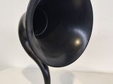 a black gramphone on a wooden stand on a white table