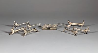 three silver figurines of animals and a dog on a table