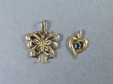 two pieces of gold and diamond jewelry on a gray surface
