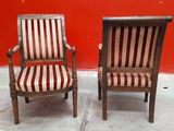 two wooden chairs with red and white striped cushions against a red wall