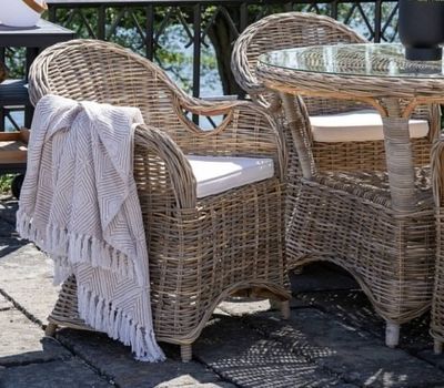 une table et des chaises en osier sur une terrasse en pierre