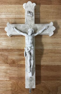 une statue de Jésus sur une croix posée sur un plancher en bois