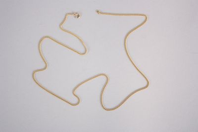 une chaîne en or surmontée d'une petite perle blanche