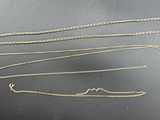 four different types of gold chains on a black surface