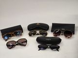 several pairs of sunglasses and a case on a white surface