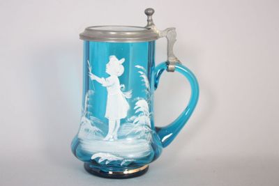 une tasse en verre bleue sur laquelle est représentée une femme