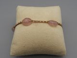 un gros plan sur un coussin sur lequel est posé un bracelet rose