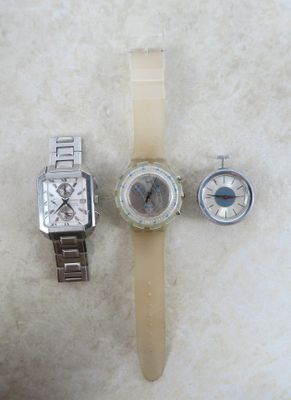 Deux montres et une montre-bracelet sont posées sur une surface blanche