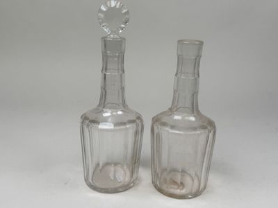 une paire de bouteilles en verre transparent posées sur une surface blanche, avec une fleur posée dessus