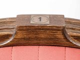 close up of a pink chair with a wooden seat and a number 1 on the back