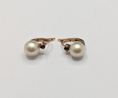 a pair of pearl and diamond earrings on a white surface