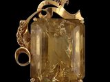 un gros plan d'un pendentif doré orné d'une pierre jaune facettée