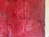 an old red book sitting on top of a wooden floor next to a wall