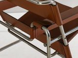 the back of a brown leather chair with a metal frame on a white surface