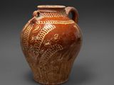 un vase marron orné de motifs sur un fond gris