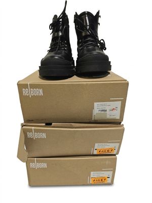trois boîtes empilées les unes sur les autres, sur lesquelles se trouve une paire de bottes noires