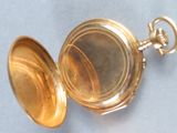 a gold pocket watch that is open on the table
