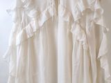 une photo d'un chemisier blanc à volants suspendu à un cintre