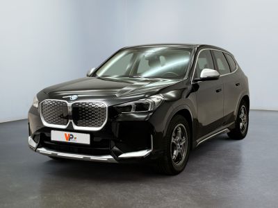 La voiture noire est garée devant un mur blanc.