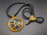 gold plated pendant with blue and black glass stones on a black cord