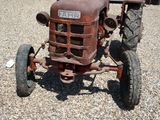 un vieux tracteur rouillé abandonné sur un terrain en gravier