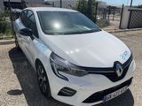 La voiture blanche est garée sur le parking, à côté d'une clôture.