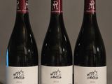 three bottles of red wine are lined up on a table