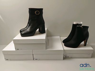 deux paires de bottines en cuir noir posées sur des cartons