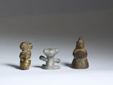 three small figurines of different shapes and sizes on a white surface