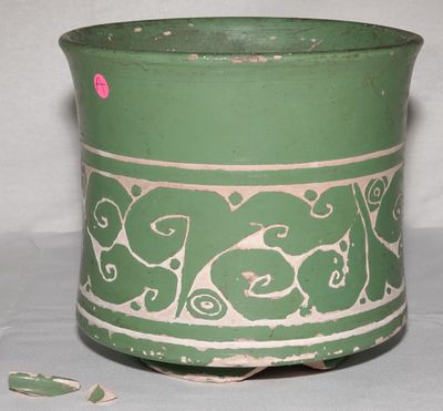 un vase vert et blanc sur lequel est collé un autocollant rose