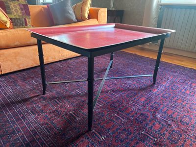 une table au plateau rouge posée sur un tapis dans un salon