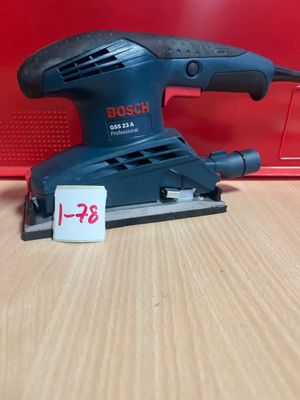 un gros plan d'une ponceuse orbitale Bosch posée sur une table en bois