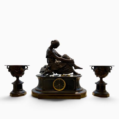une statue représentant une femme assise sur une table, à côté de trois vases