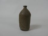 un vase brun posé sur une surface blanche