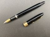 two black and gold fountain pens sitting on top of a table