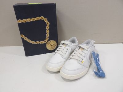white sneakers with a gold chain on a table next to a box of jewelry