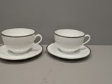 two cups and saucers on a table with a gray background