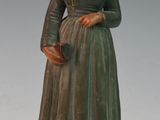 figurine représentant une femme vêtue d'une robe verte et d'un bonnet