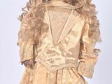 an antique doll with blonde hair wearing a gold dress and hat