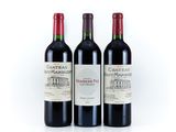 three bottles of red wine sitting next to each other on a white surface