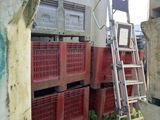 une échelle appuyée contre un mur, à côté d'une pile de caisses