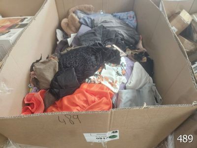 a cardboard box filled with clothes and a teddy bear